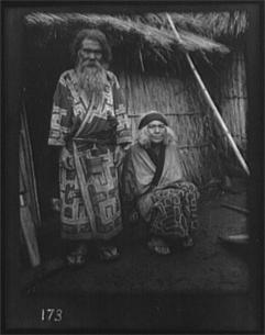 Arnold Genthe. Ainu man and seated woman at the entrance of a hut (1908)